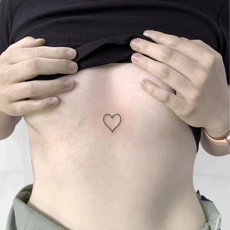 A small tattoo on a womans chest of a heart outline done as a walk in tattoo